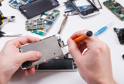 Repairman disassembling smartphone with screwdriver. Technician fixing broken phone, electronics repair service, repairer pov